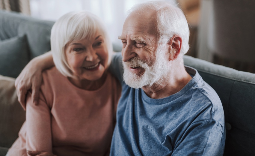 Homem branco idoso e mulher branca idosa sorrindo juntos