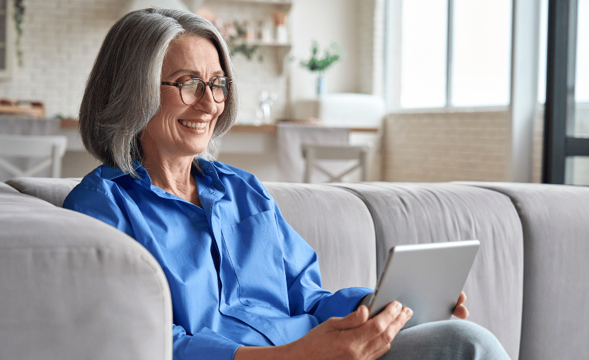 Mulher idosa sorrindo enquanto olha um tablet