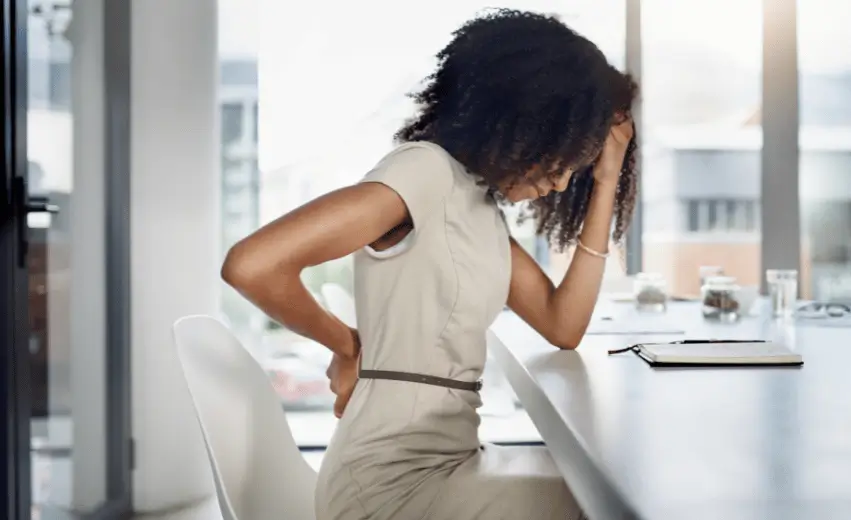 Mulher negra com dor nas costas se perguntando mentalmente se a hérnia de disco aposenta.