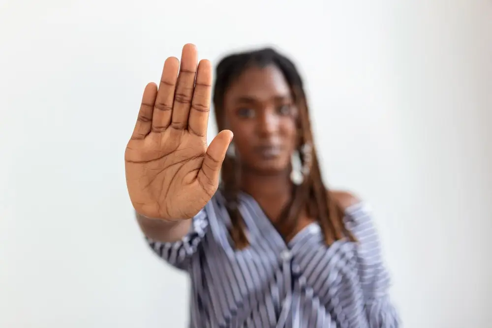 Mulher negra faz gesto de pare com a mão.