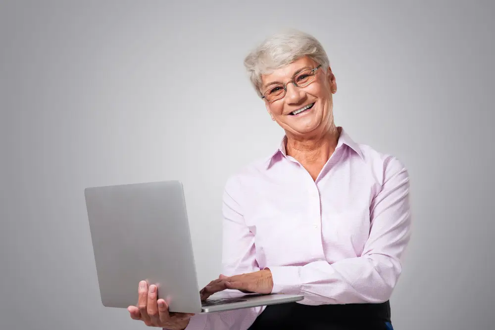 Mulher idosa sorrindo com computador.