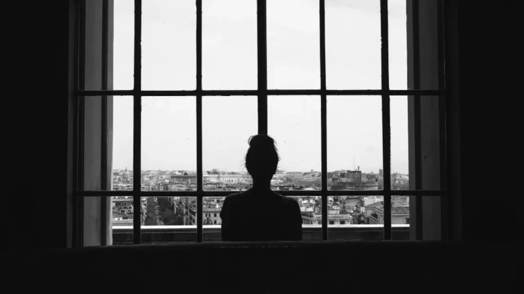 Foto em preto e branco de uma mulher na janela.
