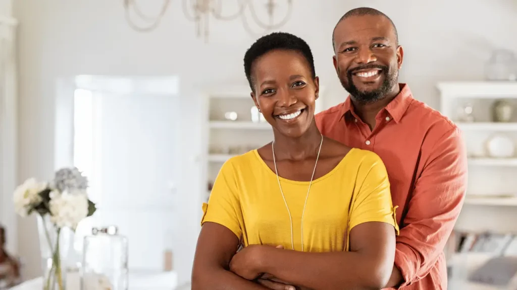 casal negro sorrindo na sala de casa