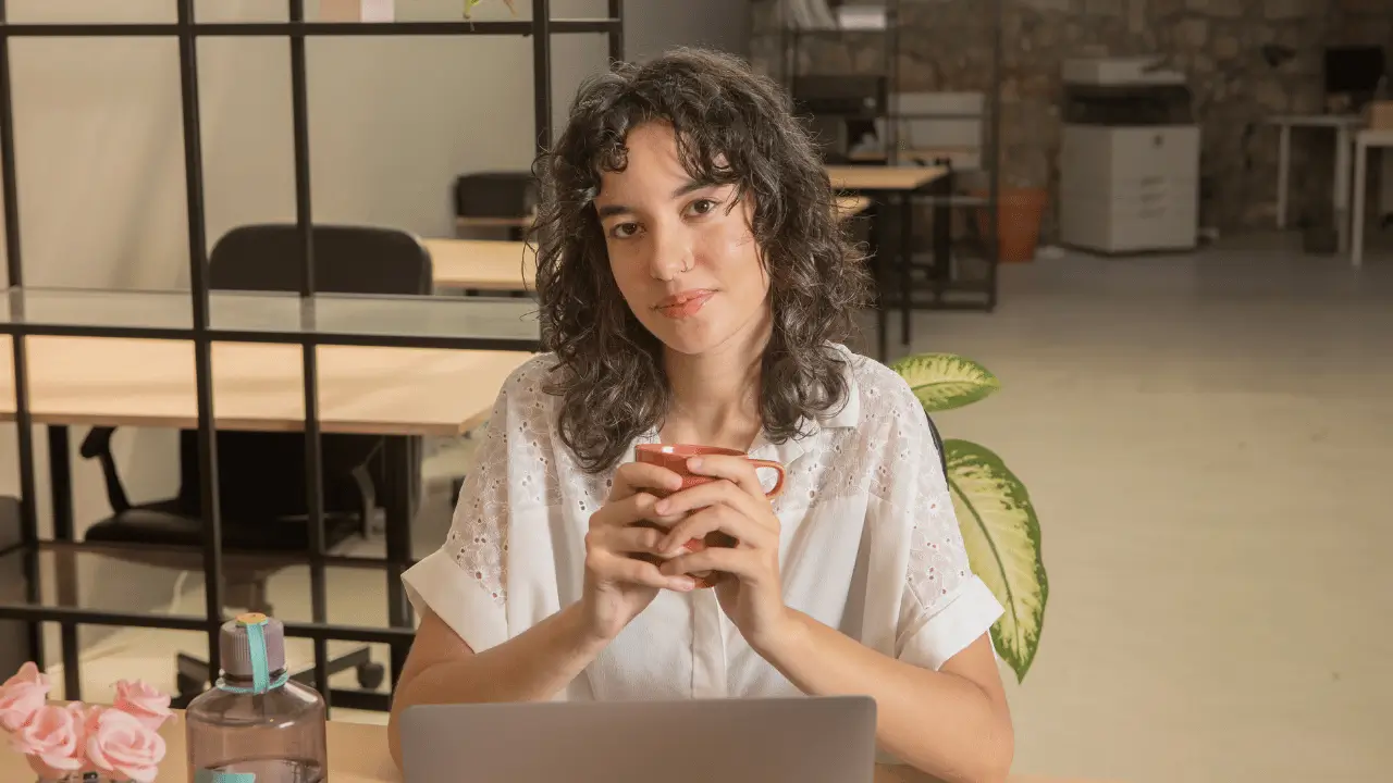 Mulher sentada com uma caneca na mão.