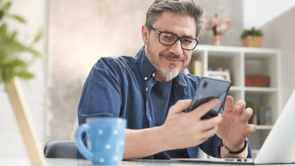 Homem de 50 anos observando o celular