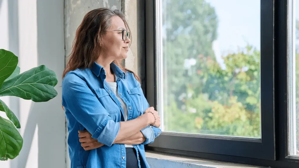 Deficiências invisíveis dão direito à aposentadoria PCD? Mulher olhando pela janela